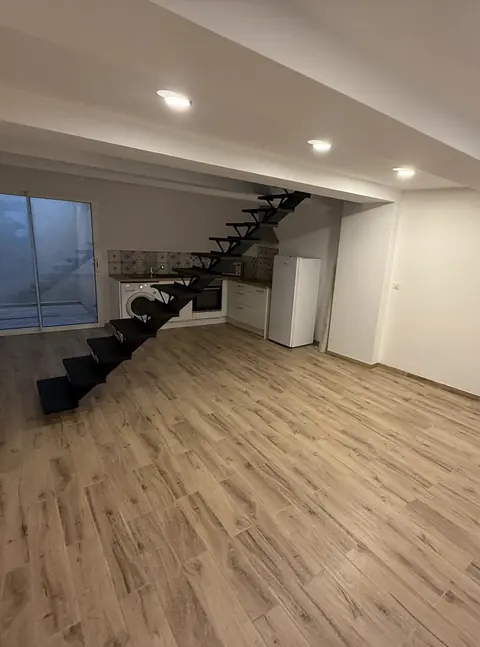 Pièce de vie rénovée avec escalier en métal et parquet clair