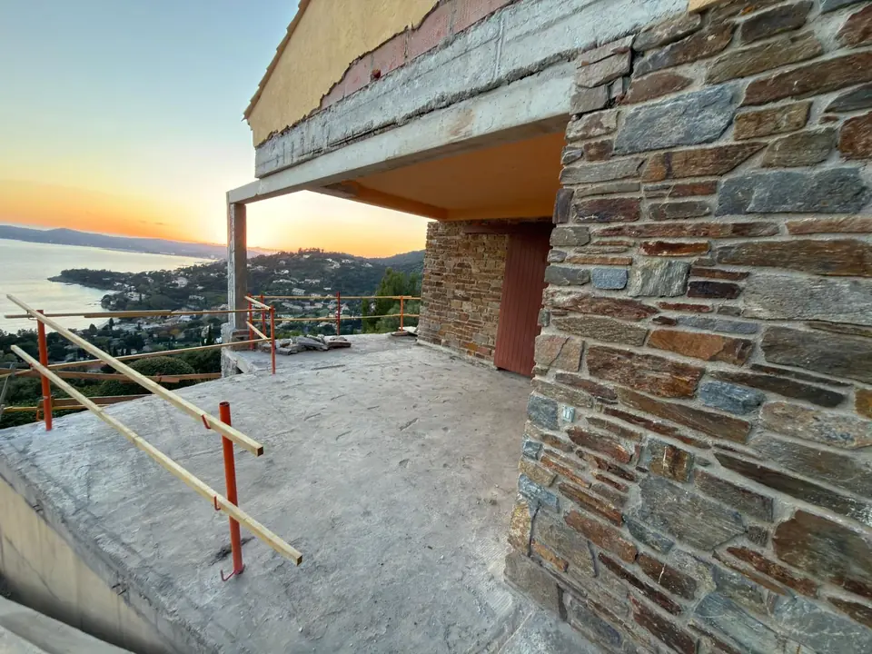 Terrasse en cours de réalisation contre un mur en pierre, vue sur la baie