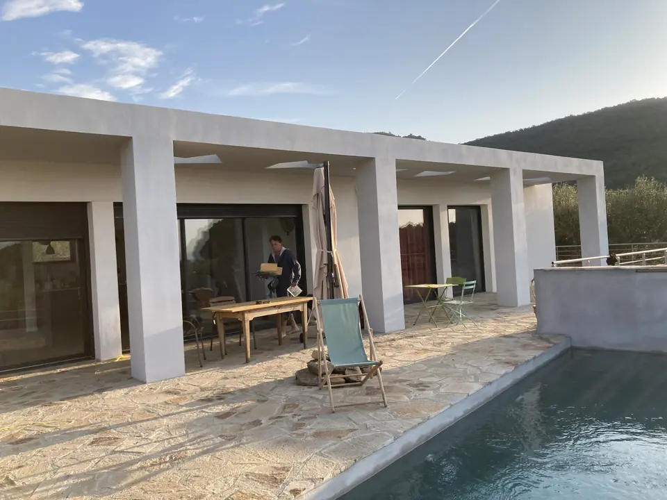Portique enduit et terrasse de la villa, vue depuis la piscine